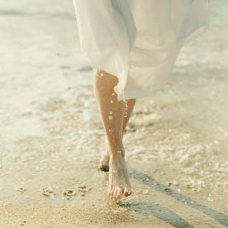 Iemand wandeld met blote voeten op het strand aan de rand van het water